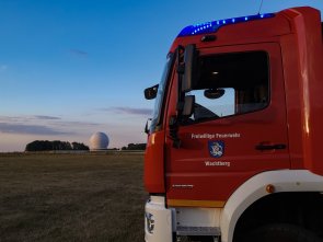 Ein Feuerwehrfahrzeug mit dem Radom im Hintergrund