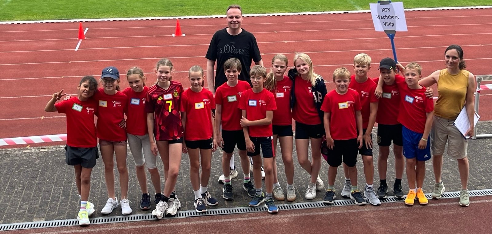 Eine Gruppe Kinder in Sportkleidung und zwei Erwachsene im Stadion